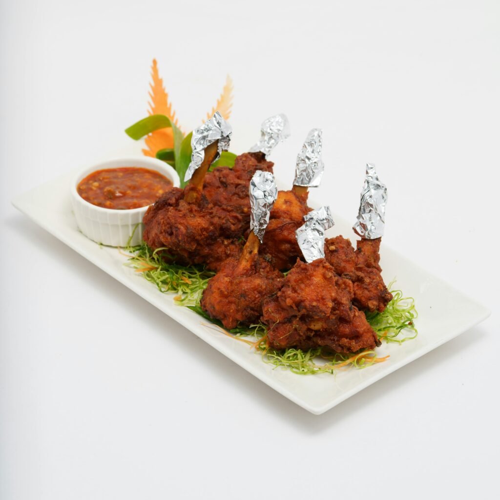Delicious crispy chicken lollipops served with a spicy dipping sauce and garnished with fresh greens.