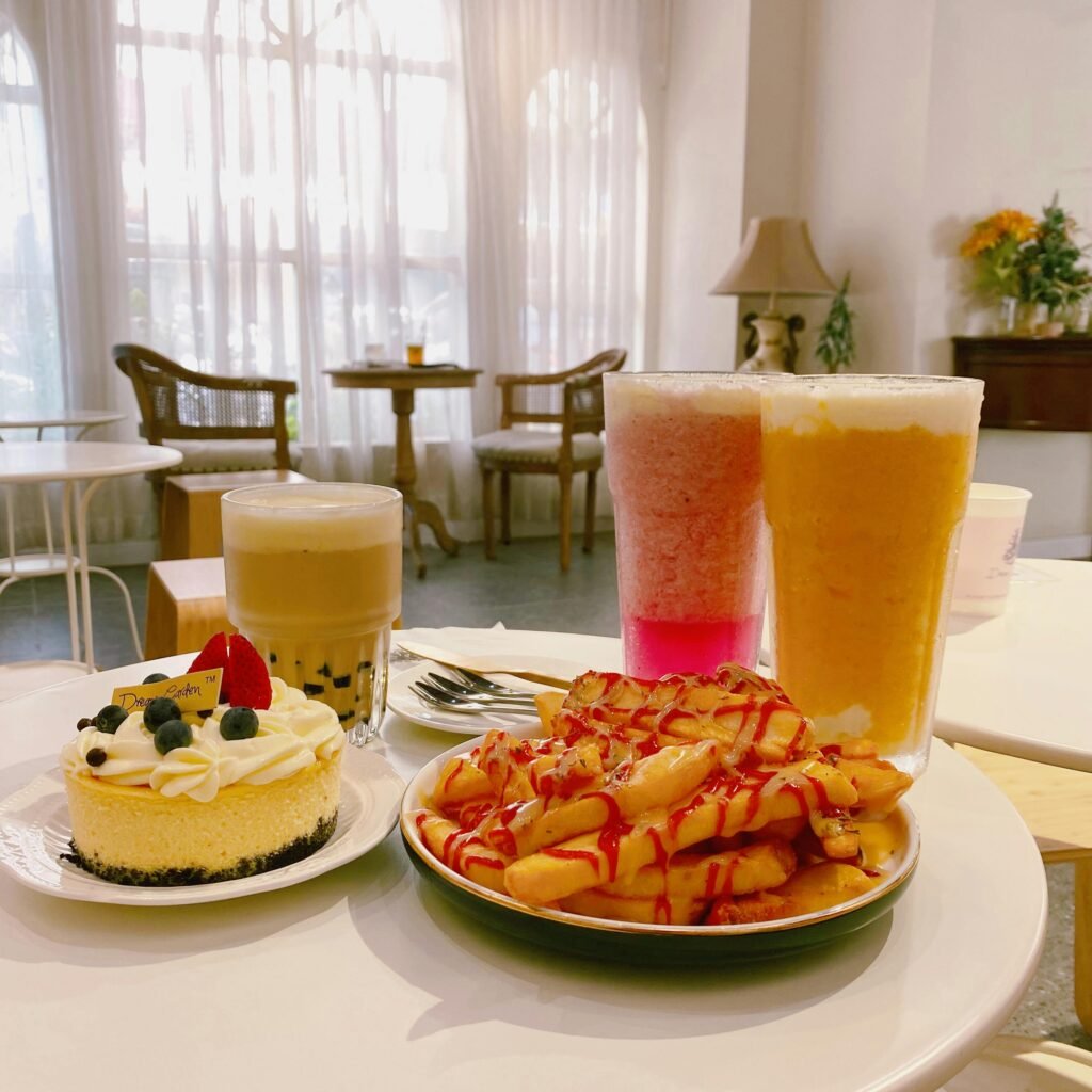 Inviting cafe table with cheesecake, bubble tea, juices, and waffles.