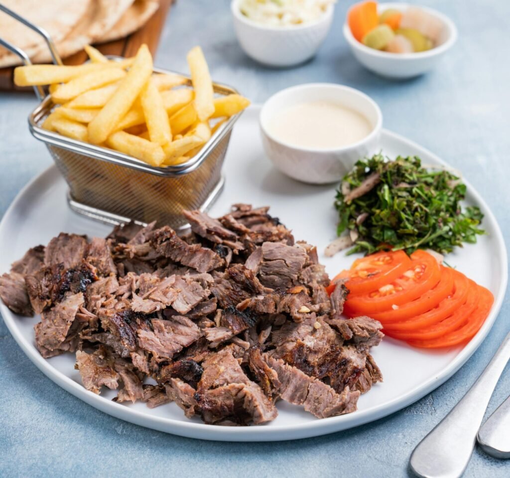 A mouth-watering Middle Eastern shawarma platter with fries and fresh vegetables.